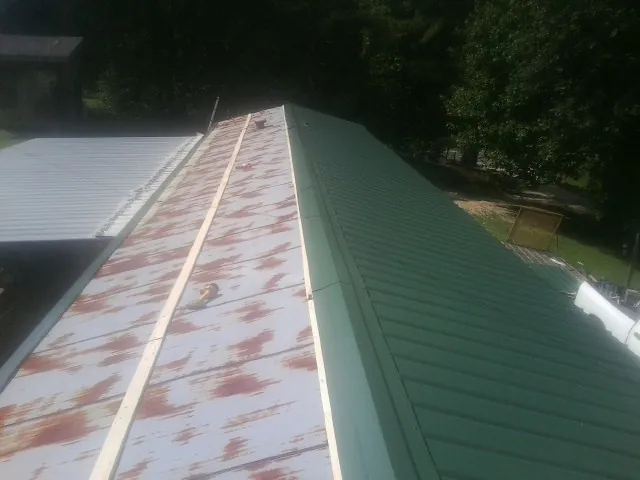 Old rusted panels beside newly installed green metal roofing — Wind Damage Roof Repair by Roofing Brothers in Dupo