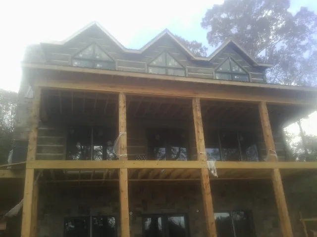 Dormers and porch framing on a large log home under construction — Roof Coating work by our crew in Dupo