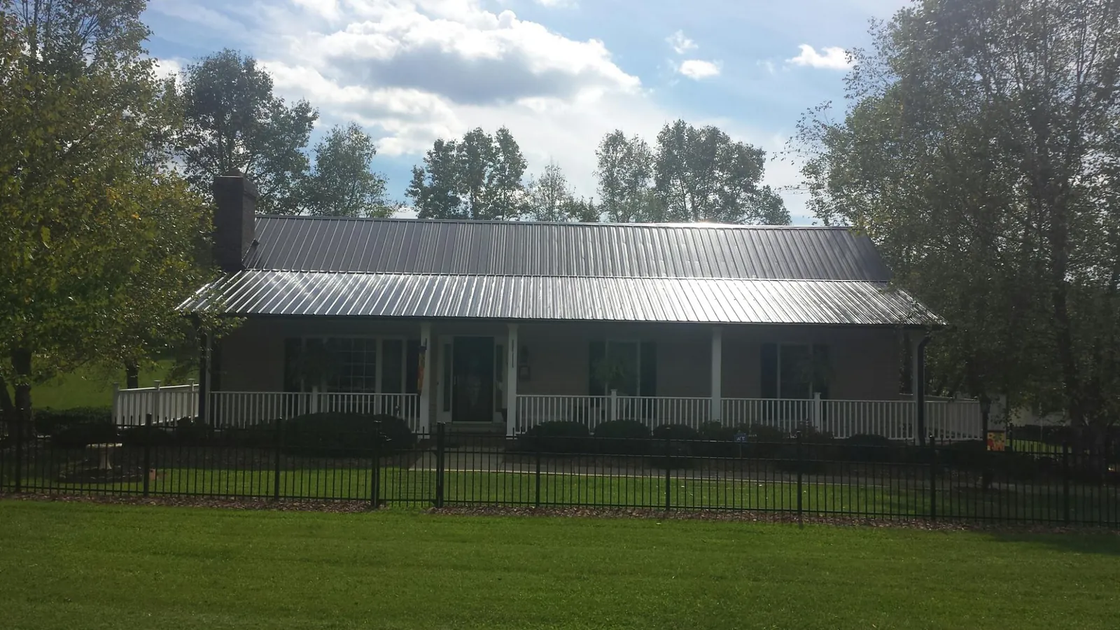 Gray metal roof on a brick ranch with a full width front porch — Gutter Guard Installation work by our crew in Dupo
