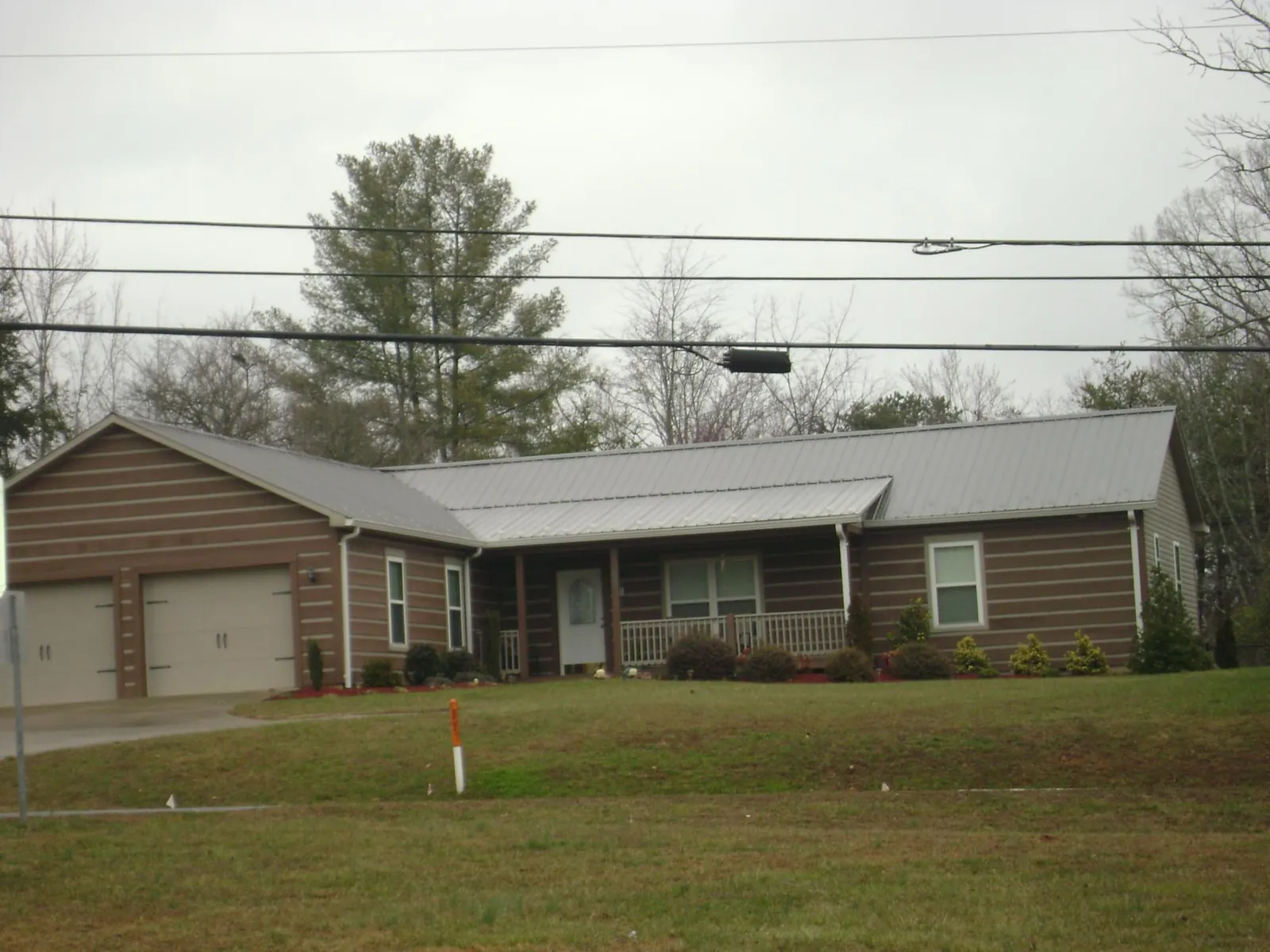 Gray metal roof on a log sided ranch home with a front porch in Dupo