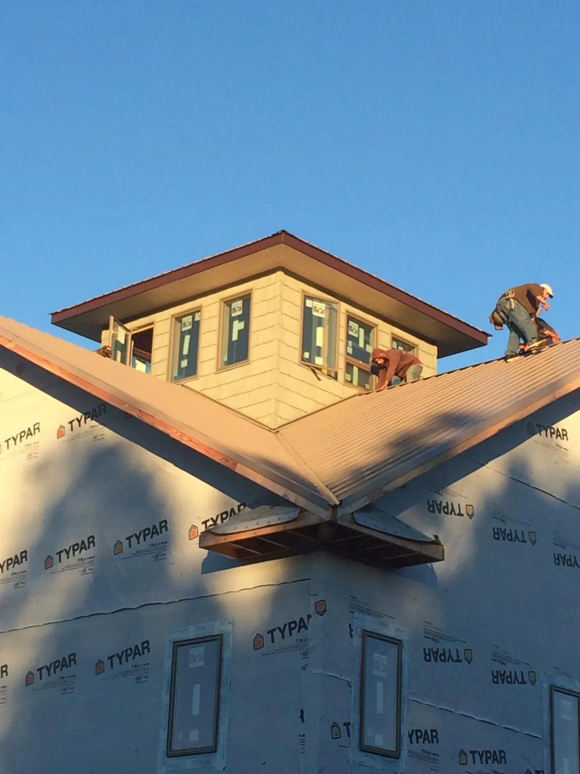 Roofers working around a rooftop cupola on a new metal roof at sunset — Roof Waterproofing in Dupo by Roofing Brothers
